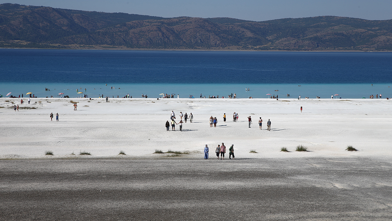 Günün son ışıklarında Salda Gölü`nün bembeyaz kumsalı ve serin turkuaz suyunda yürüyenler, güneşin göle veda ederken suda ve kumsalda bıraktığı göz alıcı parıltılarını izlemenin keyfini yaşıyor.  