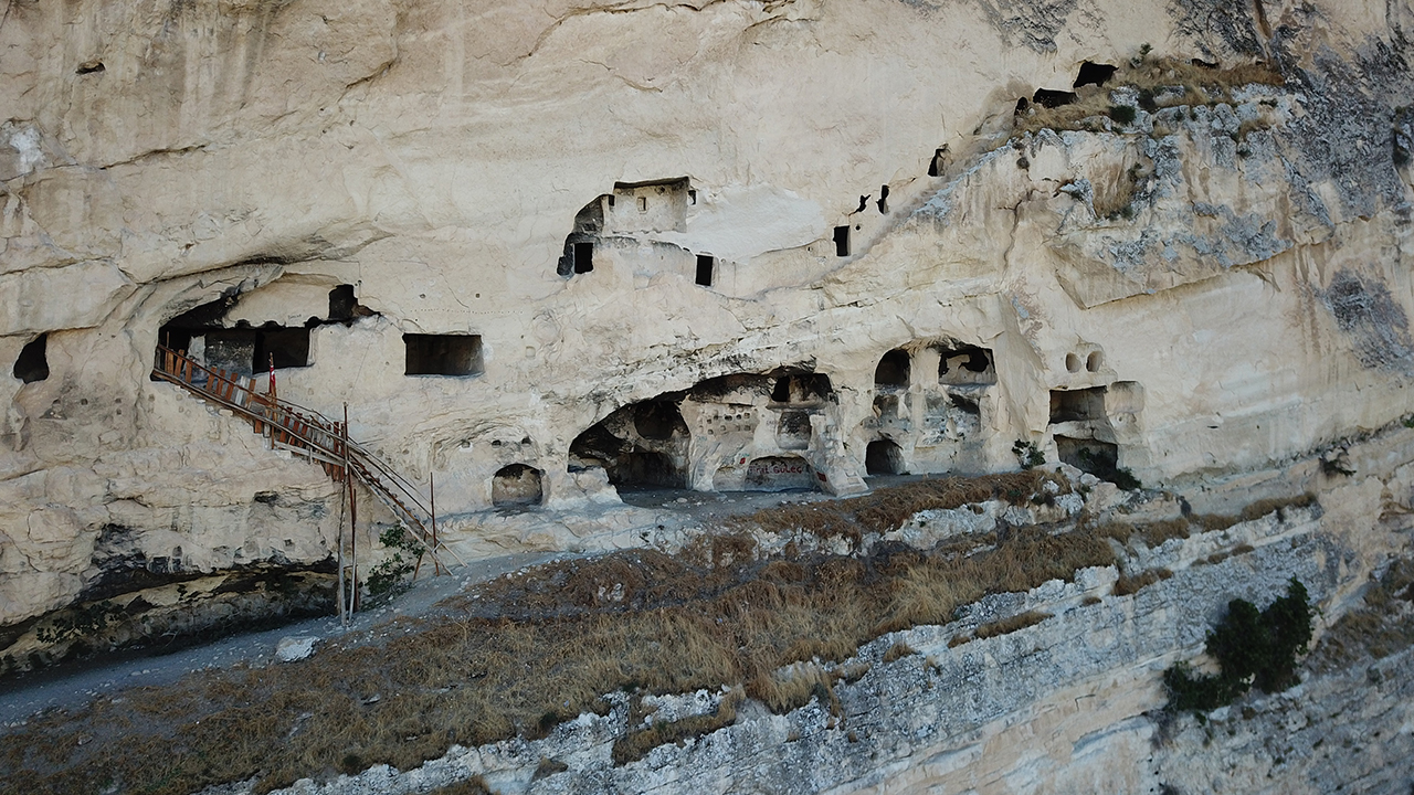 İlçe merkezinin batısında Tahar Çayı Vadisi`nin yukarıya doğru uzanan sarp kalker kayalarına konut amaçlı oyulan 20 civarında odanın kim tarafından yapıldığı bilinmiyor.