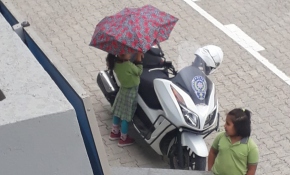 Kırık şemsiyesi ile polis motosikletini yağmurdan korudu