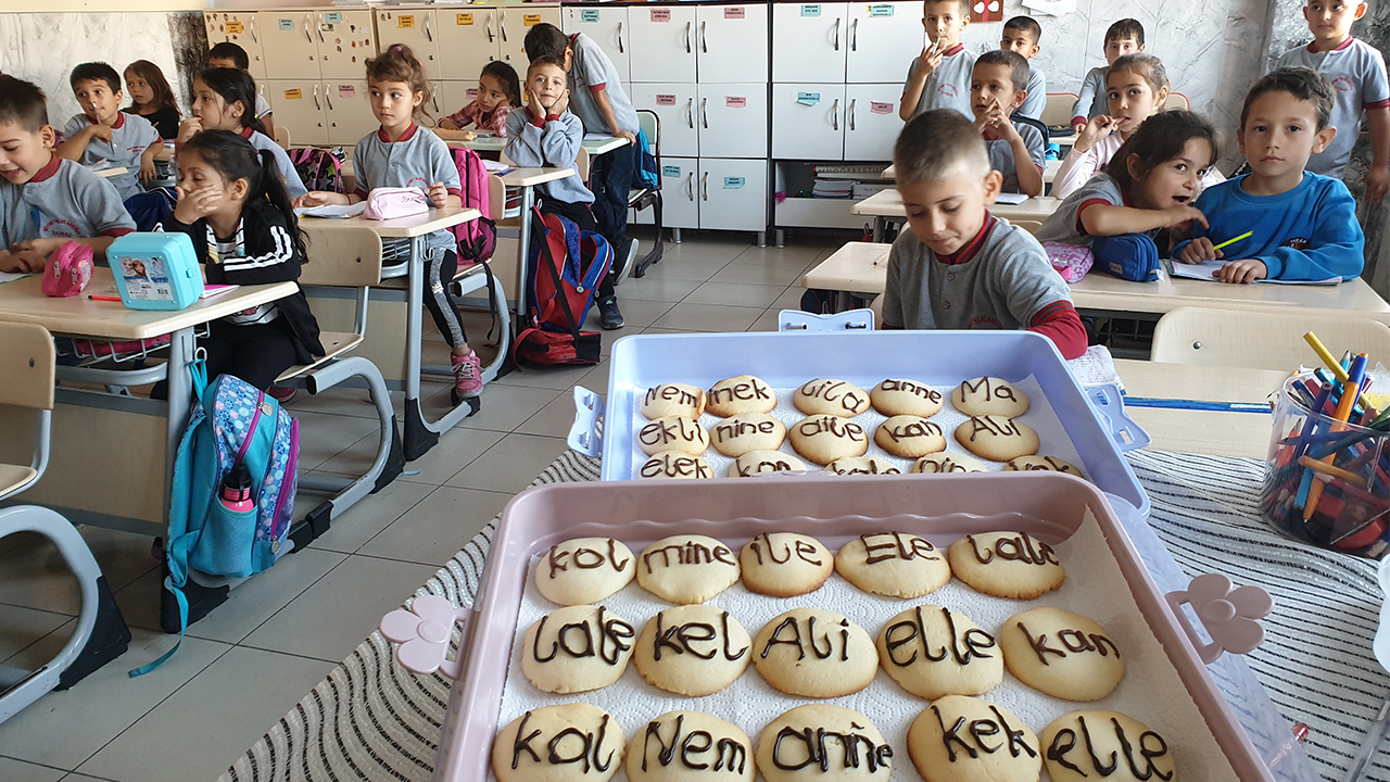 Kadirli Mehmet Nuri Arıoğlu İlkokulu birinci sınıf öğrenci velileri, öğretmen Dönay Paşaoğlu öncülüğünde üzerinde hece ve kelimelerin bulunduğu kurabiye hazırlıyor.