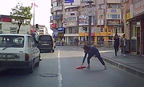 Yola düşen bayrağı araçlar üstünden geçmesin diye aldı