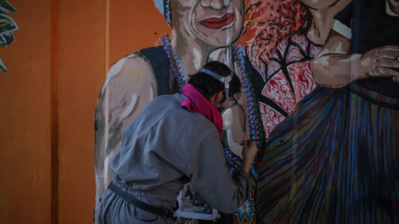 Fotoğrafta, duvara resim yapan bir kadın ressam görülüyor.