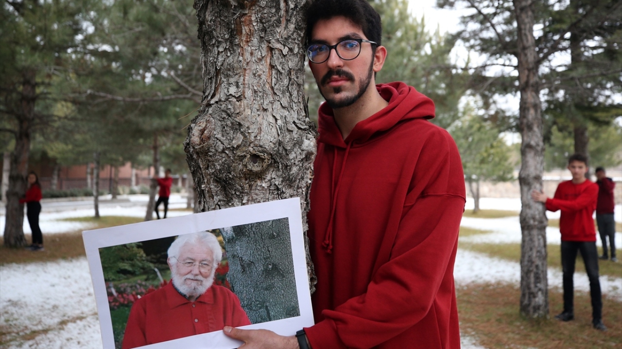 Etkinlikte kırmızı kazak giyen Celalettin Ekinci ve öğrenciler, Hayrettin Karaca`nın bir ağaca sarılmış haldeki fotoğrafına atfen okulun bahçesindeki çam ağaçlarına sarıldı.