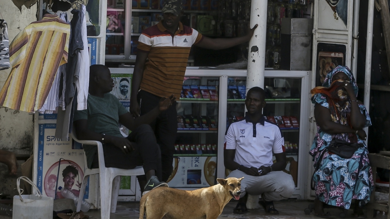 Fotoğrafta, cep telefonu malzemeleri satan bir dükkanın önünde dinlenen vatandaşlar görülüyor.