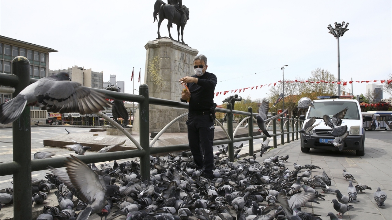 Boş kalan Ulus Meydanı`ndaki güvercinleri bir polis memuru besledi.