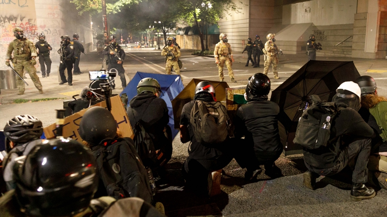 Bazı göstericiler gösteriye müdahale eden federal güvenlik güçlerine karşı şemsiyelerinin ardında siper aldı.