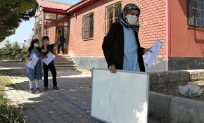 Elinde yazı tahtasıyla kapı kapı dolaşarak öğrencilerine ders anlatıyor