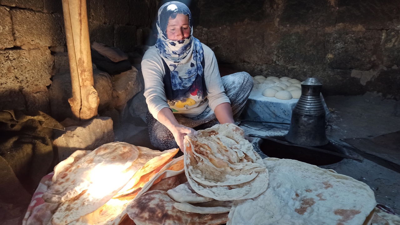 Yakılan tandırla birlikte yoğun duman altında zorlu bir ekmek pişirme telaşına düşen kadınlar, arada bir tandır evlerinden dışarı çıkarak temiz hava alıyor. 