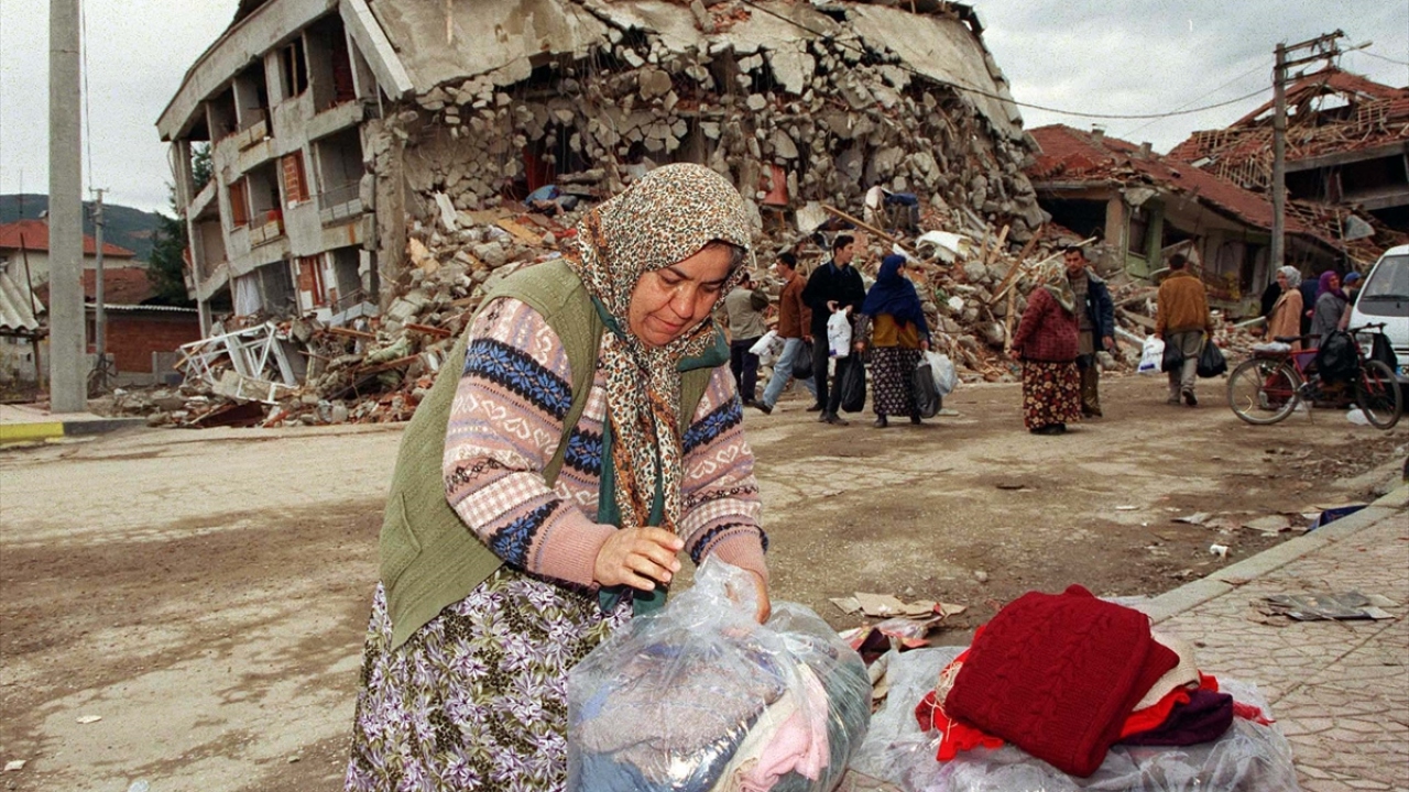 21 Kasım 1999`da Düzce depreminin ardından depremzedeler, gelen giyecek yardımları ile yağmur ve soğuk havayla mücadele etmeye hazırlanıyor. (Arşiv)