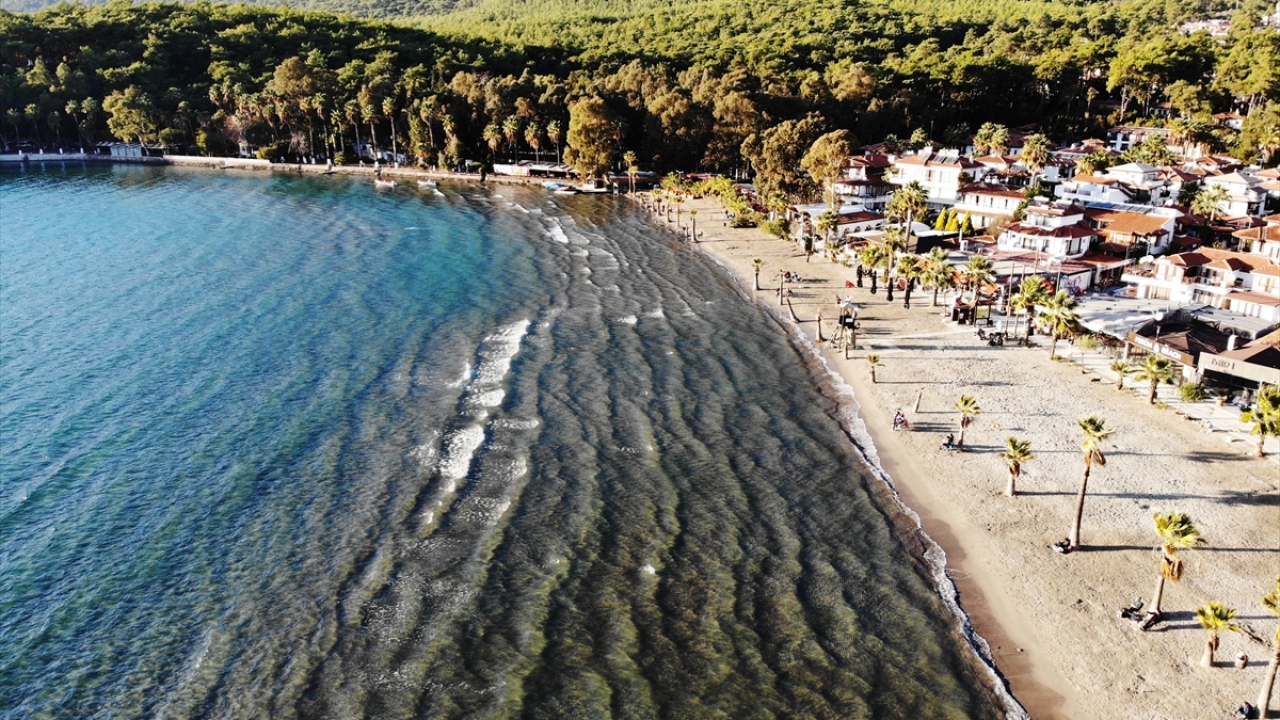 Bölgeye gelen ziyaretçiler, sahil kenarında yanlarında getirdikleri sandalyelerde otururken güneşin batışını izliyor.