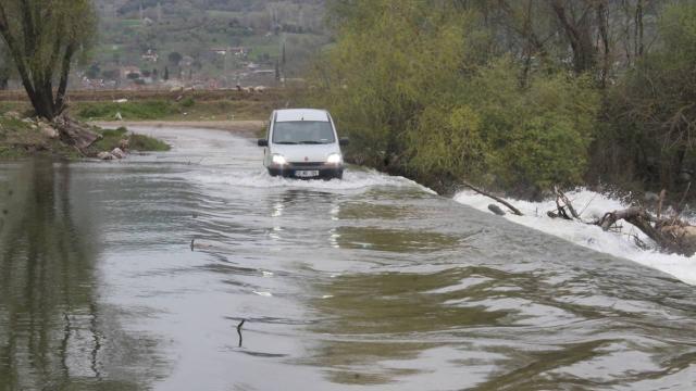 Evlerine kısa yoldan ulaşmak için su altında kalan köprüden geçiyor