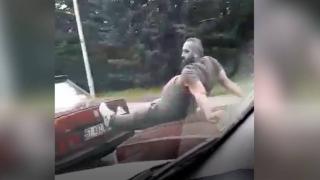 Seyir halindeki otomobilin üzerine çıktı, ayaklarıyla arızalı aracı itti