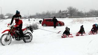 Motosiklete bağladığı kızaklarla çocukları eğlendirdi
