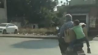 Küçük çocuk motosikletten düşmemek için koliye tutundu