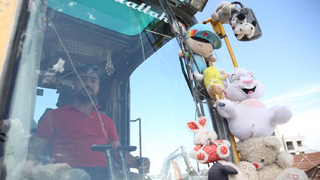 Kaldırdığı enkazlardan çıkardığı oyuncakları kepçesine asıp çalışıyor