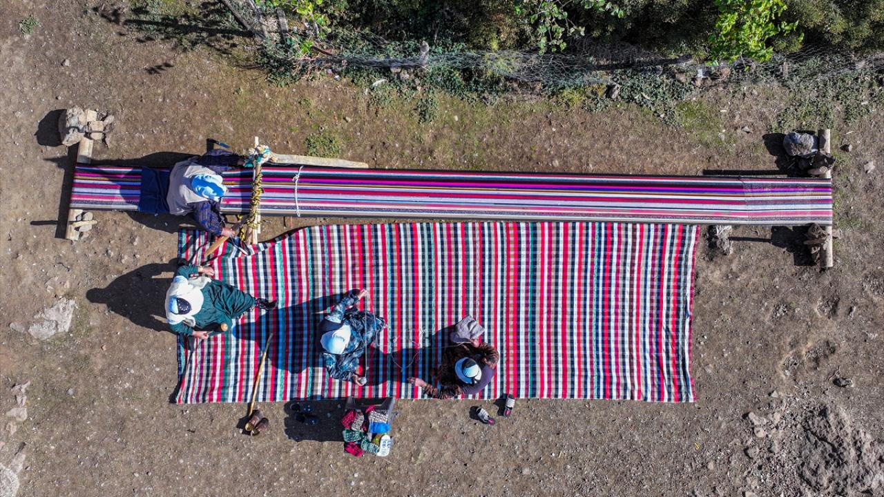 Evinin bahçesindeki tezgahta asırlık yöntemle kilim dokuyor