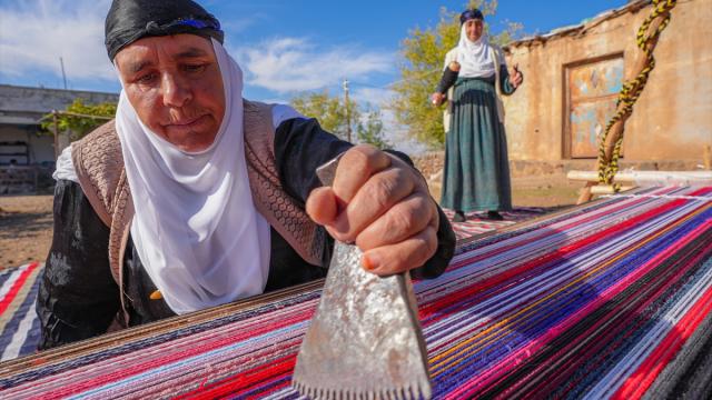 Evinin bahçesindeki tezgahta asırlık yöntemle kilim dokuyor