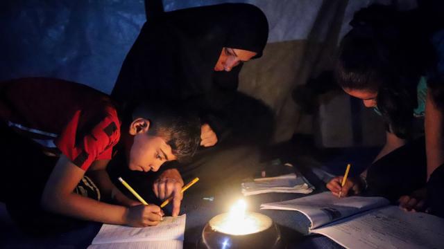 Gazze’de yerinden edilen öğrenciler, ödevlerini mum ışığında yapıyor