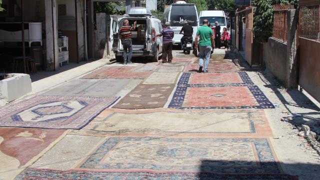 Adana'da mahalle sakinleri asfaltlanmayan yoldaki çukurları halılarla kapattı