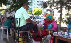 Palyaço kostümüyle hem ayakkabı boyuyor hem insanları eğlendiriyor